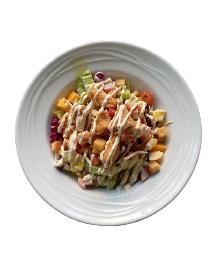 Ensalada César con lechuga, tomate, trozos de pechuga de pollo, croutons y salsa César.