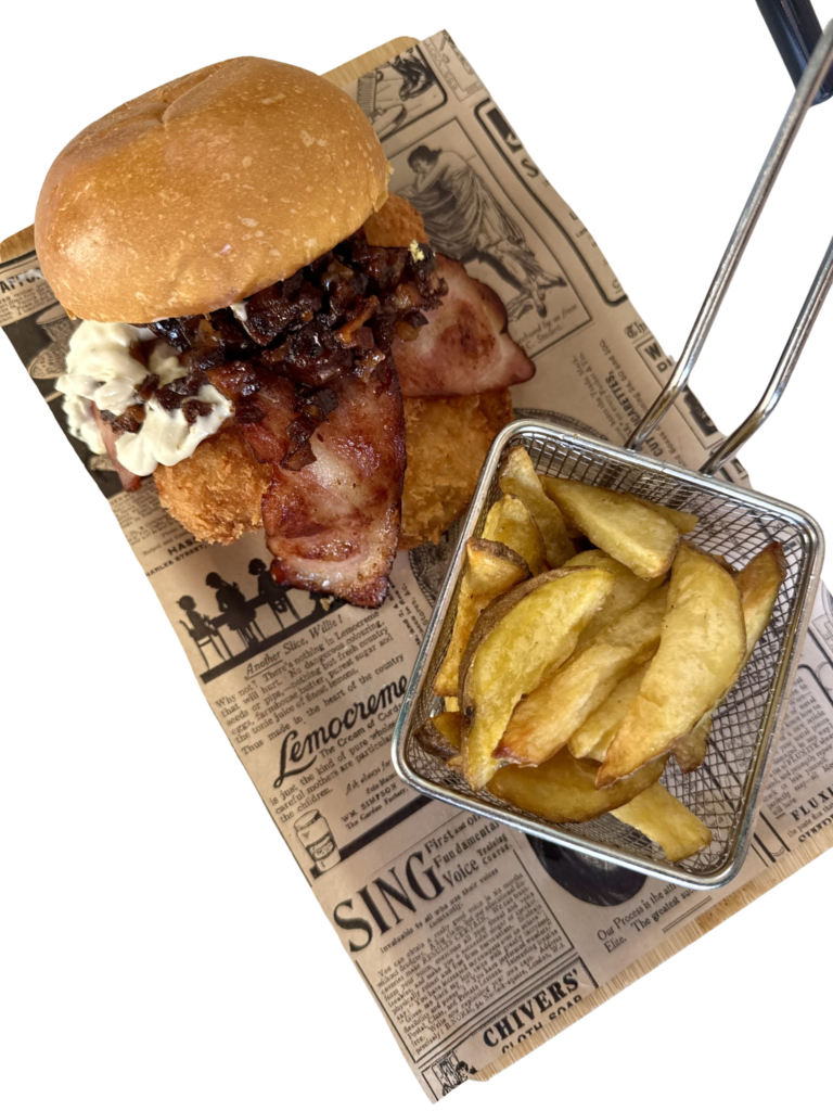 Hamburguesa de pollo crujiente con salsa de queso roquefort, bacon, mermelada de bacon y lechuga, acompañada de patatas fritas.