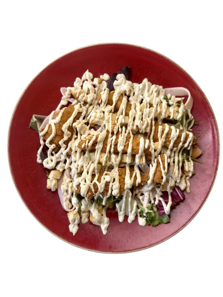 Ensalada César gourmet con lechuga, queso manchego, croutons de pan, pollo crujiente, tiras de pavo y salsa César casera.
