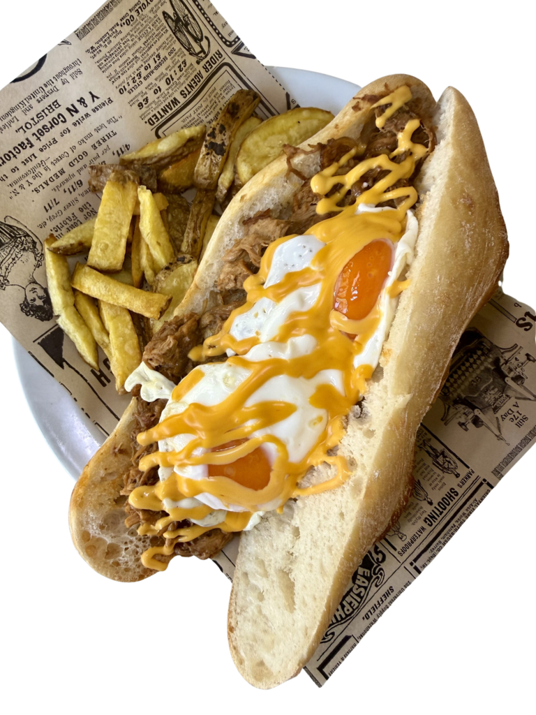 Figa Tatia: Pull pork de costillas y carrillada con cebolla caramelizada, cheddar fundido y 2 huevos fritos servidos con patatas fritas. Ideal para una comida deliciosa.